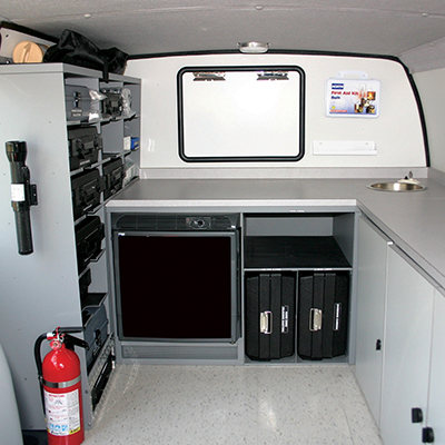 View from cab showing refrigerator, sink, passenger side storage and lockable cabinetry